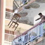 Un bulgaro che da un balcone del Palazzo ex Cirio di Mondragone lancia una sedia durante le proteste per il focolaio Covid (foto Ansa)