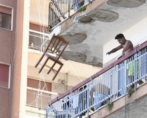 Un bulgaro che da un balcone del Palazzo ex Cirio di Mondragone lancia una sedia durante le proteste per il focolaio Covid (foto Ansa)